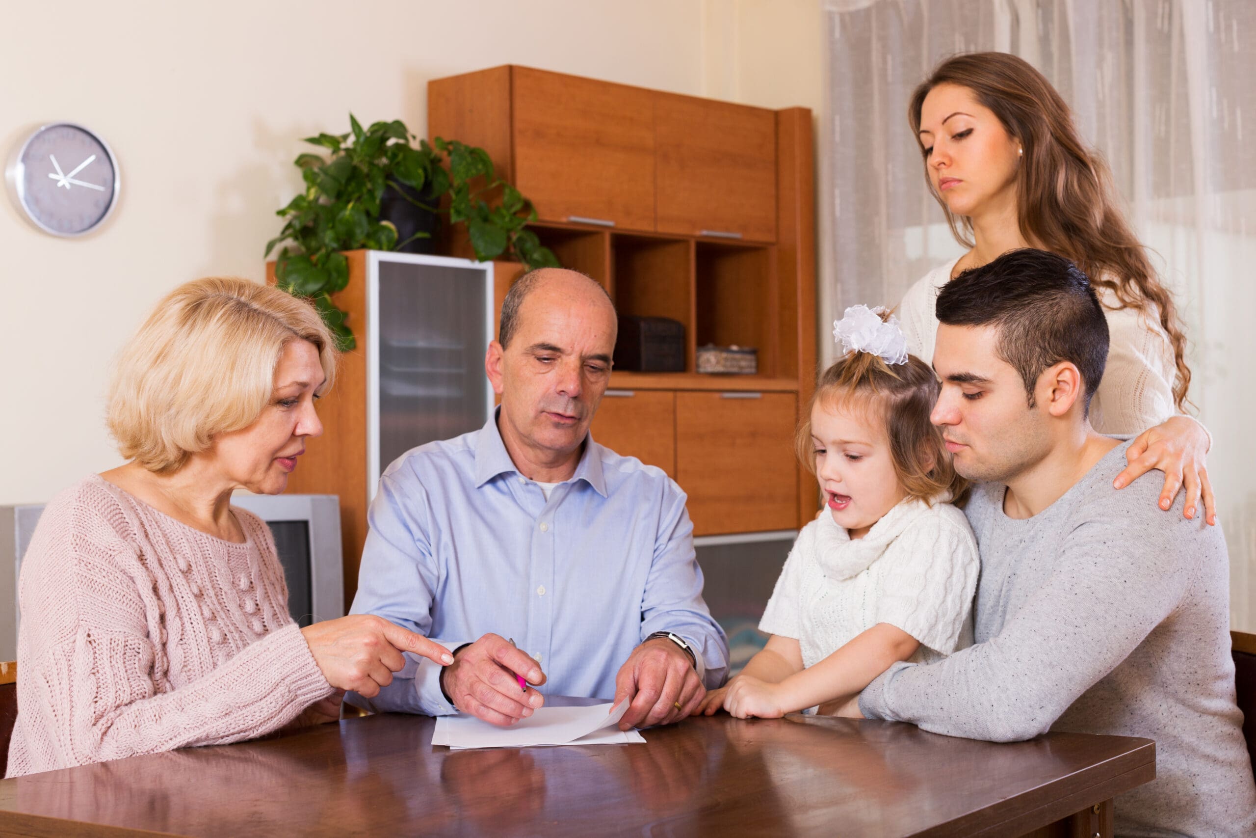 Serious multigenerational family members with bills and without money at the table  indoor